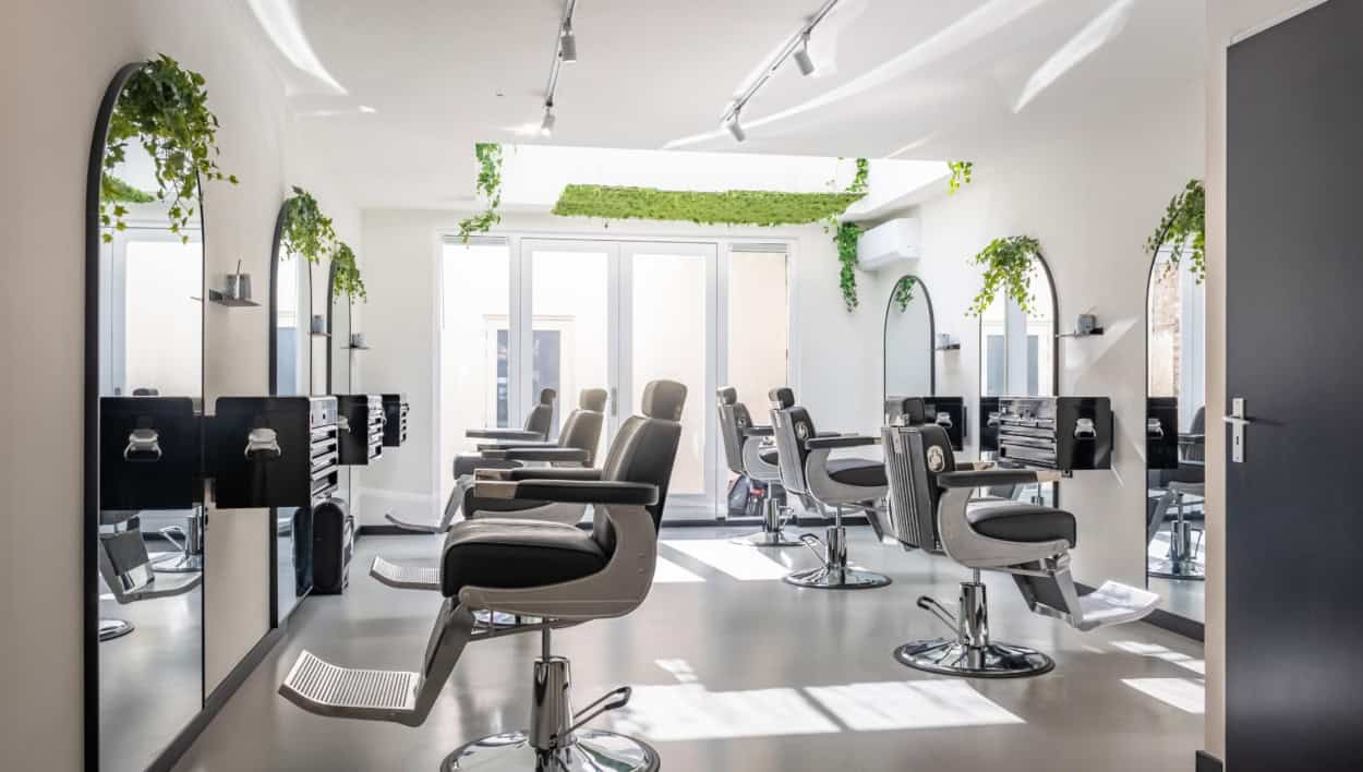 De salon van United Coupes met boogspiegels, planten en kappersstoelen