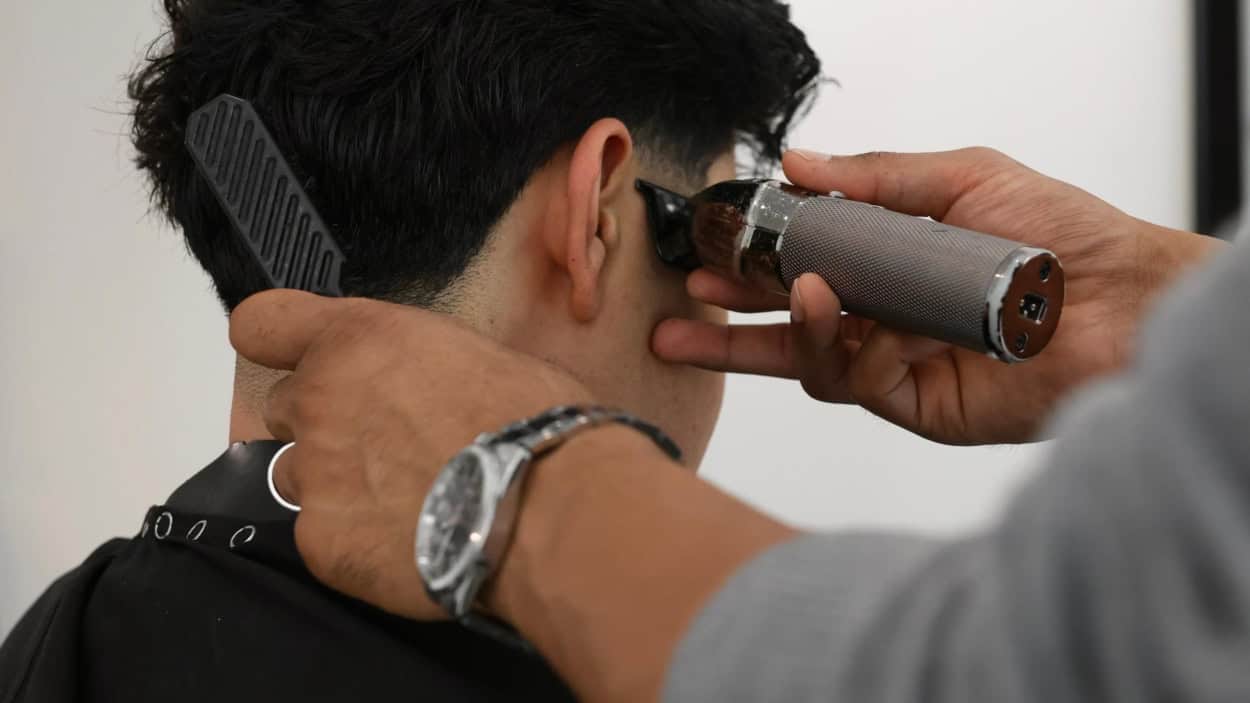 Barbier werkt met de tondeuse de haarlijn bij